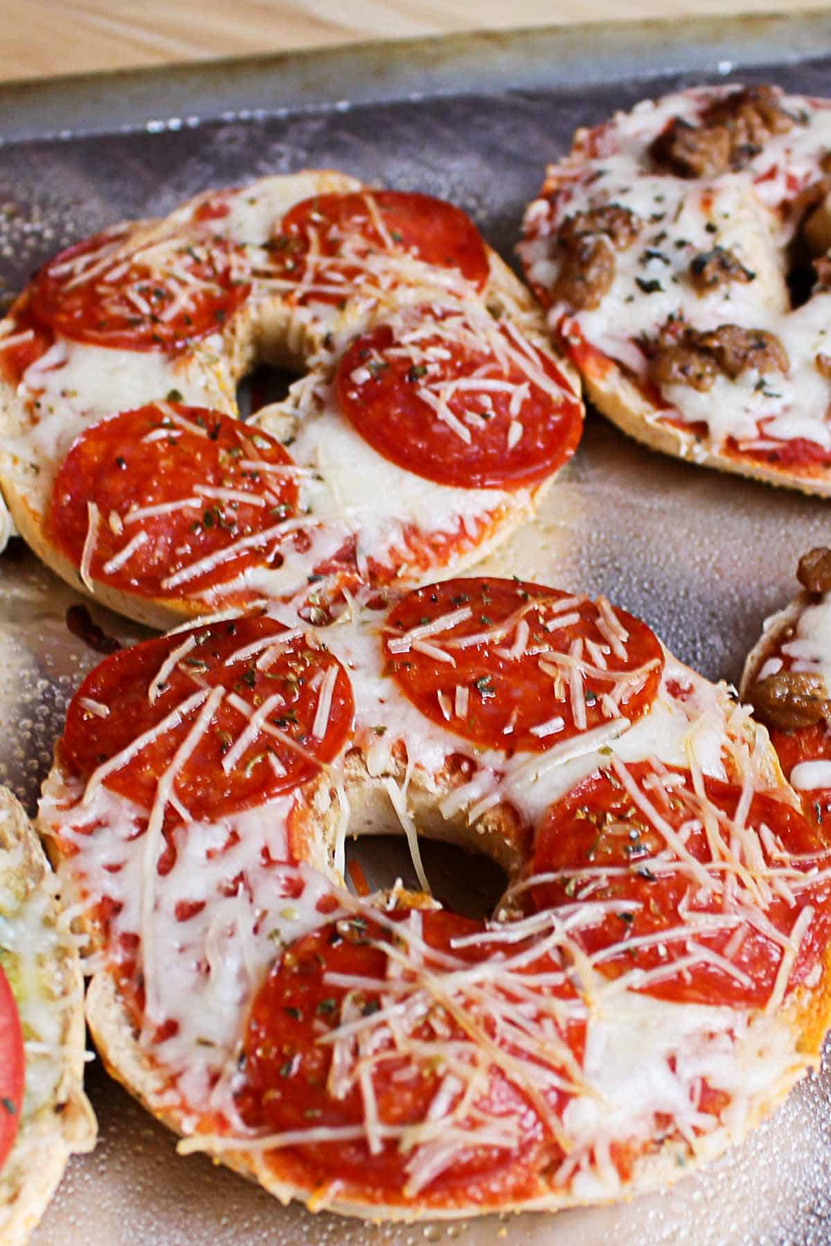 Tray of hot, melted freezer-friendly pizza bagels with pepperoni, melted mozzarella cheese, and crispy edges.