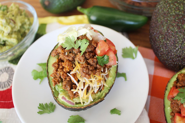Halved avocado with beef, cheese, onion, tomato, cilantro and guacamole mixture - the Guano-Taco.