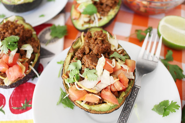 Halved avocado with beef, cheese, onion, tomato, cilantro and guacamole mixture - the Guano-Taco. 