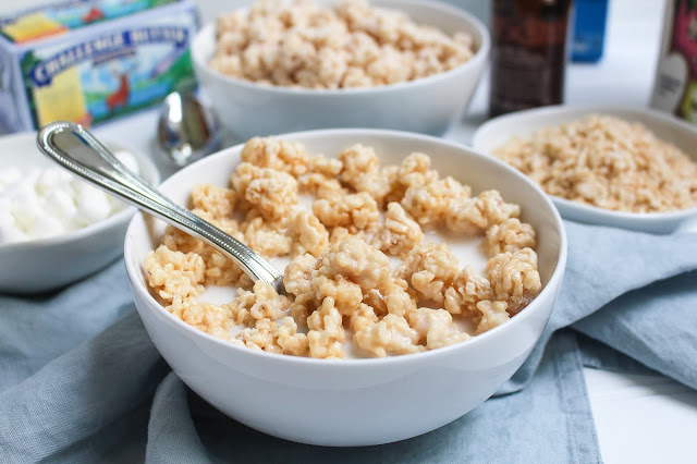 A close up photo of a bowl of the Homemade Rice Krispies Treats Cereal with a spoon in it.