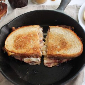 Close-up of a grilled cheese sandwich with peanut butter, jelly, and bacon in a skillet.