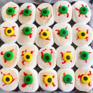 Uncut rectangle of Halloween s'mores bars topped with toasted marshmallows decorated as bloodshot candy eyeballs