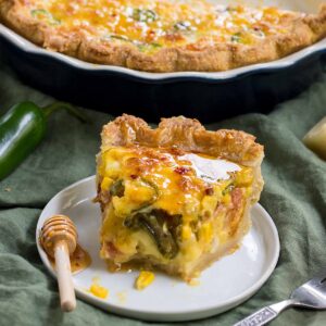 Slice of Southwestern quiche with cheese, peppers, and jalapeño on a plate.
