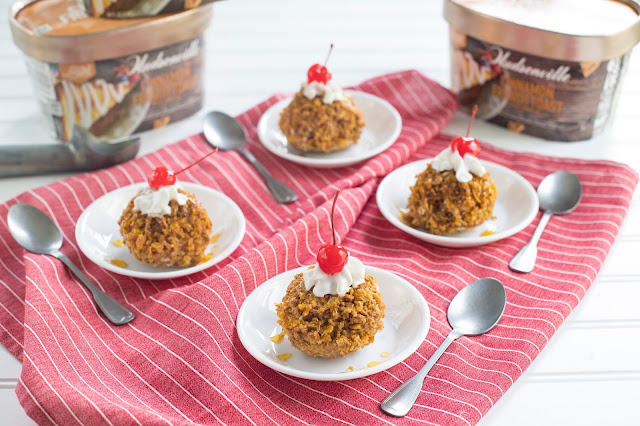 Easy "Fried" Ice Cream in a bowl with whipped cream and cherry on top. The fried ice cream is made of ice cream coated in crushed cereal. A total of four fried ice cream sundaes are present.