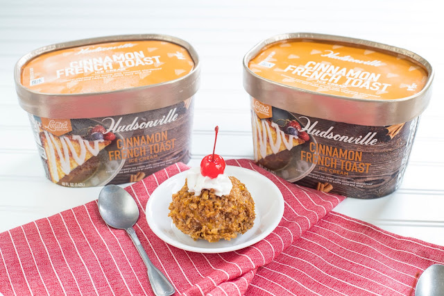 Easy "Fried" Ice Cream in a bowl with whipped cream and cherry on top. The fried ice cream is made of ice cream coated in crushed cereal. It is flanked by two buckets of Hudsonville Cinnamon French Toast ice cream. 