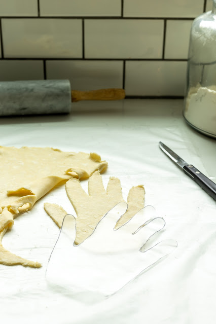 The flattened dough cut into a hand shape using a cut out paper hand tracing. 