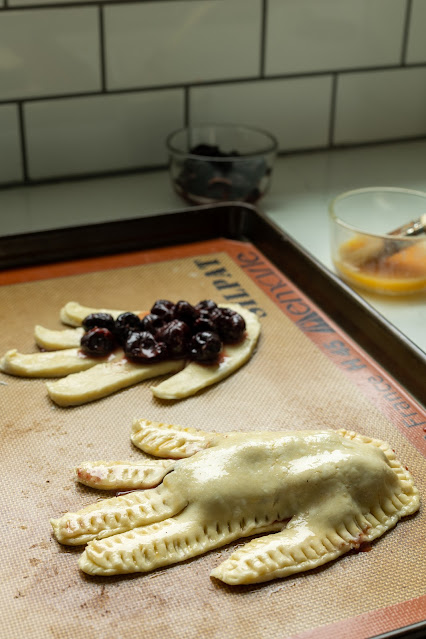 Uncooked sweet Halloween Hand Pies. One is already filled and another has the cherry filling laid out but not covered.