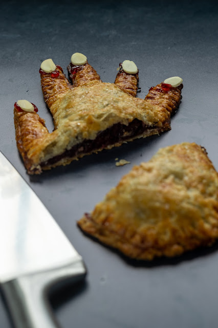 Cooked, sweet, Halloween Hand Pie shaped like a hand with almond slivers for fingernails, cut in half.