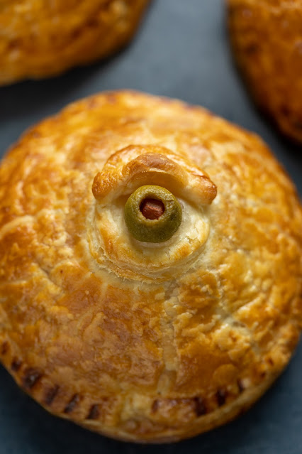 Cooked savory Halloween Hand Pies shaped like an eyeball with a pimento olive center.