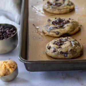 Freshly baked cookies with chocolate chips on a baking sheet.
