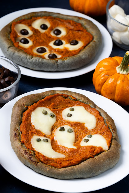 Halloween Pumpkin Pizzas with black crust and fun, spooky designs including cheese with caper ghosts and cheese and olive eye balls.