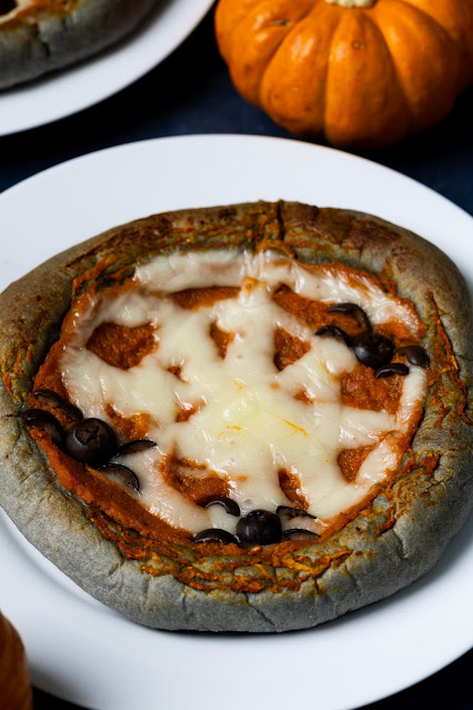 Halloween pumpkin pizza with black crust pizza and spider web design.