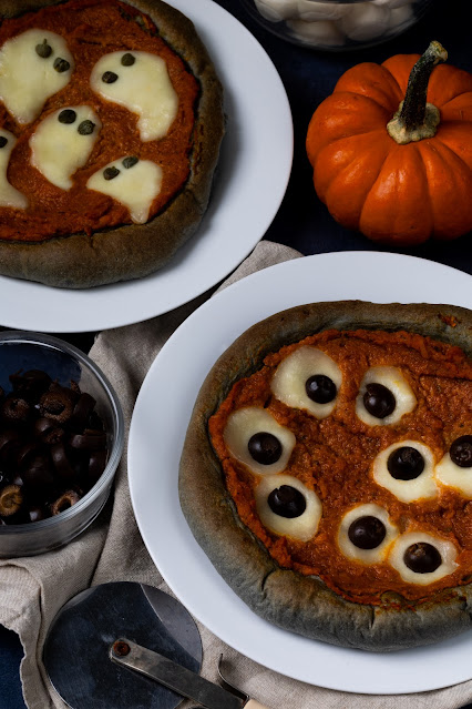 Halloween Pumpkin Pizzas with black crust and fun, spooky designs including cheese with caper ghosts and cheese and olive eye balls.