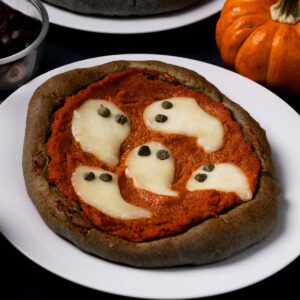 Halloween Pumpkin Pizzas with black crust and fun, spooky designs including cheese and caper ghosts.
