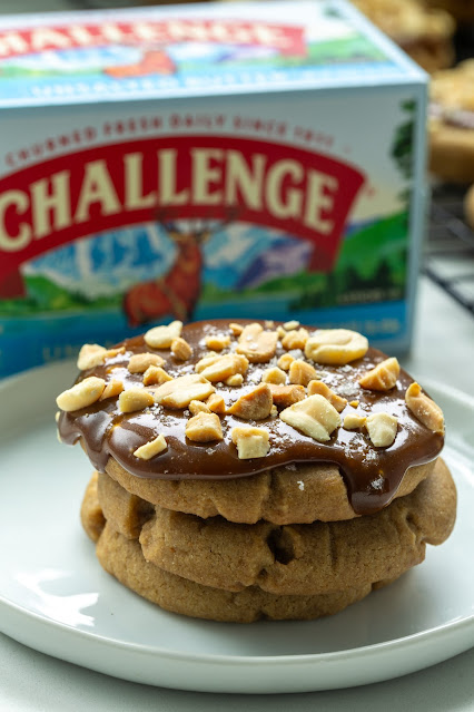 Tamarind Caramel Cookies on a plate. The cookies are made of a brown sugar cookie with a tamarind caramel on top topped with sea salt and roasted peanuts. 