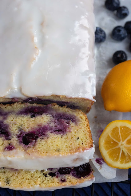 Sliced whole lemon blueberry cake. The lemon icing covers the cake but the interior shows beautiful blueberry swirls.
