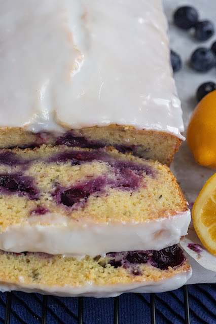 Sliced whole lemon blueberry cake. The lemon icing covers the cake but the interior shows beautiful blueberry swirls.