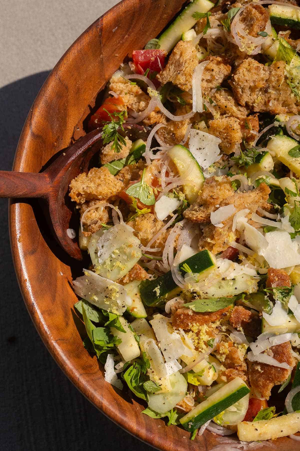 Fresh zucchini, bread croutons, and herbs in a wooden bowl for summer salad.