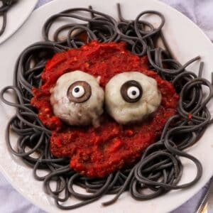 Spaghetti and meatball eyeballs plated over black squid ink pasta with red marinara sauce for Halloween dinner